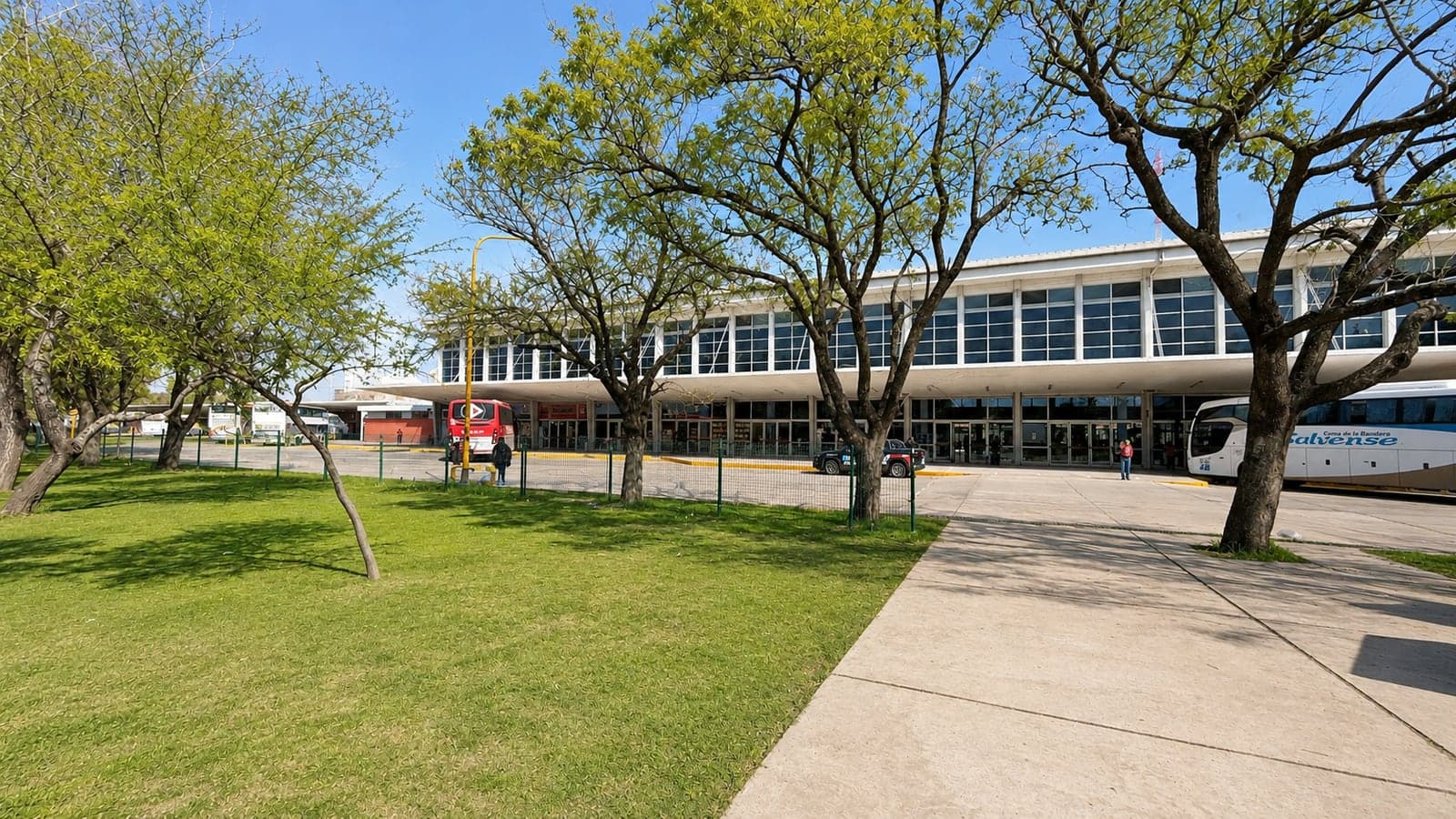 Fachada de la Terminal vista desde el parque, con los árboles, el césped y los ómnibus detenidos frente al edificio
